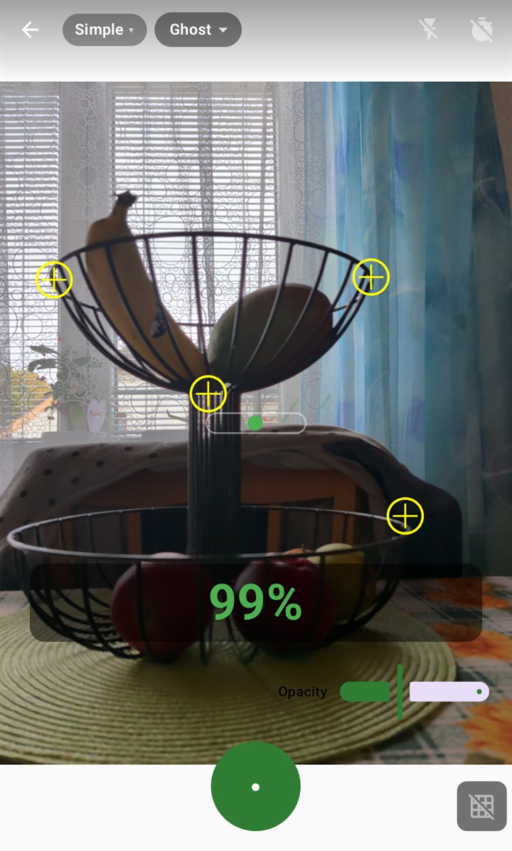 The MyReFrame camera lining up a fruit bowl: the reference photo laid over the live view as a ghost, four yellow anchor points on the bowl, an alignment score of 99 % in green, the opacity slider and the shutter.